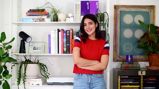 Day in the life; a woman stood in front of a stack of books and drawings